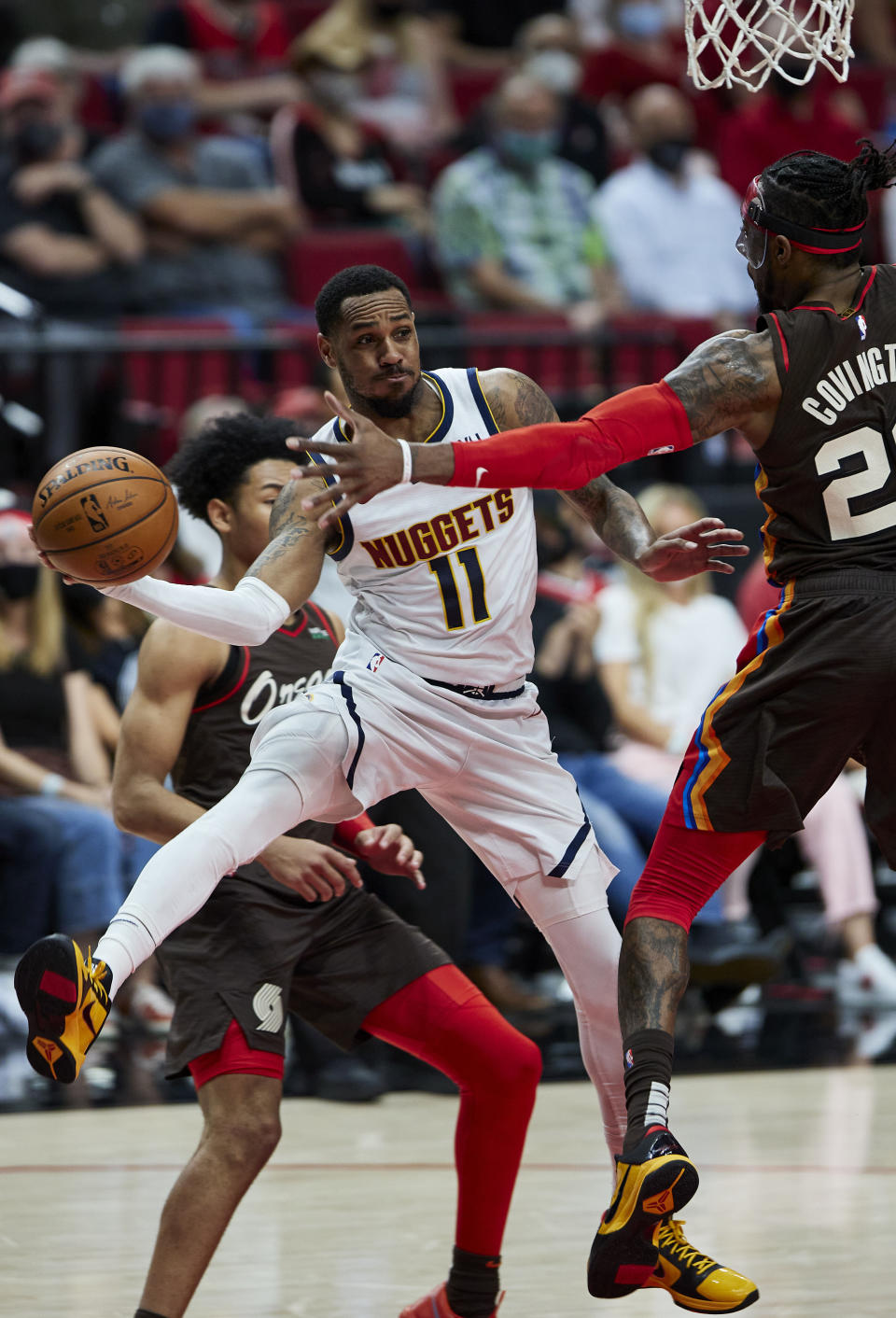 Denver Nuggets guard Monte Morris (11) passes the ball around Portland Trail Blazers forward Robert Covington, right, during the first half of Game 6 of an NBA basketball first-round playoff series Thursday, June 3, 2021, in Portland, Ore. (AP Photo/Craig Mitchelldyer)