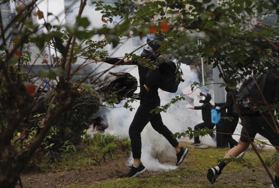 Protestors brave police tear gas as they clash in Hong Kong, Sunday, Oct. 6, 2019. Shouting "Wearing mask is not a crime," tens of thousands of protesters braved the rain Sunday to march in central Hong Kong as a court rejected a second legal attempt to block a mask ban aimed at quashing violence during four months of pro-democracy rallies. (AP Photo/Kin Cheung)