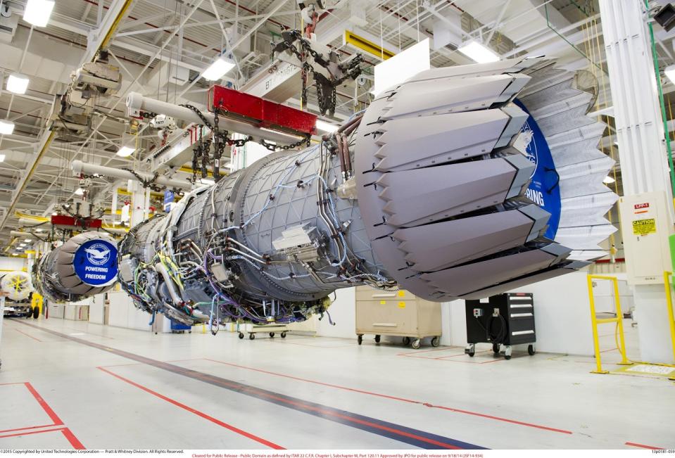 Aircraft engine hoisted on an elevated assembly line.