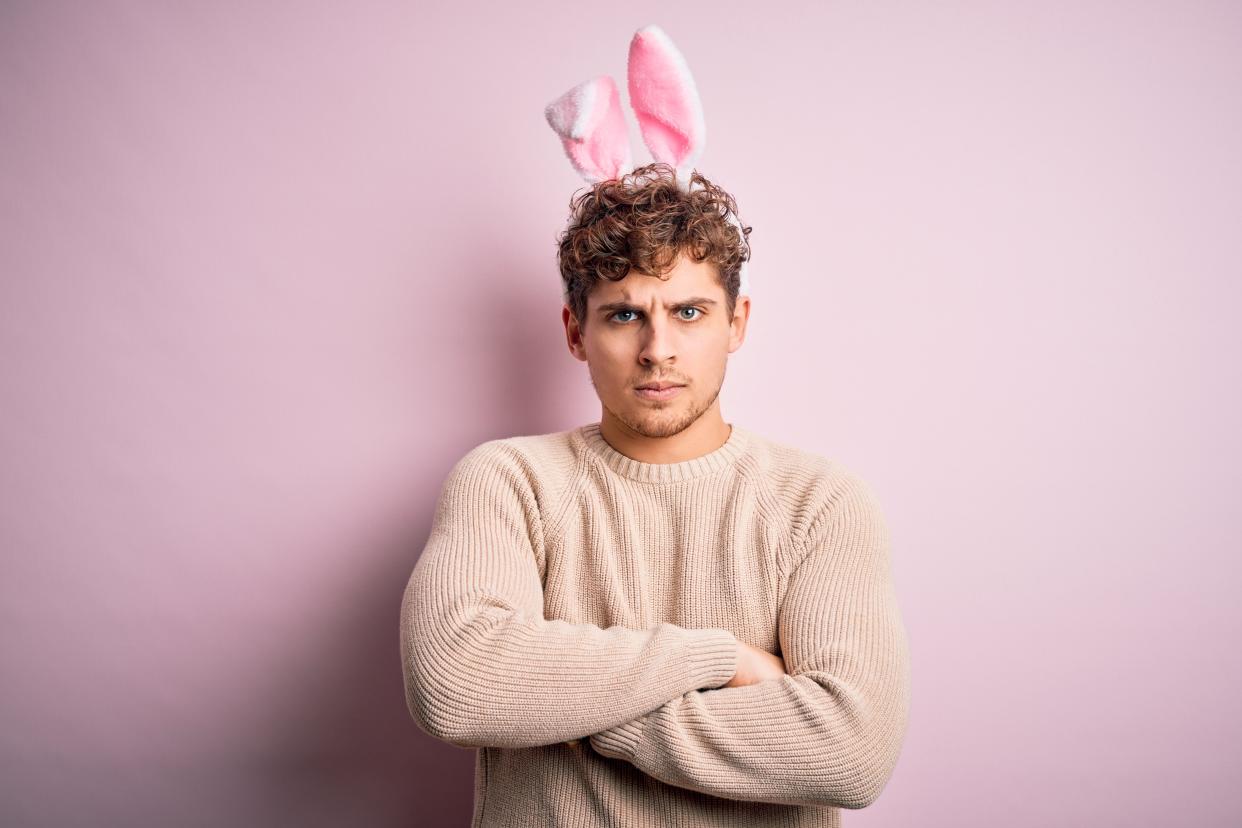 flexible working Young handsome blond man wearing easter rabbit ears over isolated pink background skeptic and nervous, disapproving expression on face with crossed arms. Negative person.
