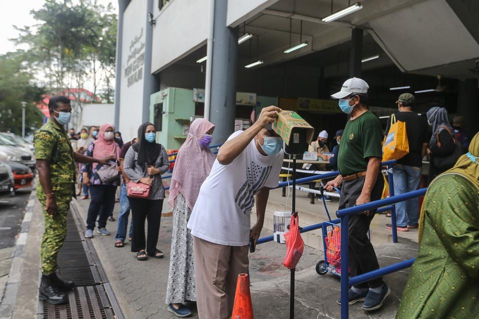 People have their temperature checked before entering the Seksyen 6 wet market in Shah Alam May 11, 2021. — Picture by Yusof Mat Isa