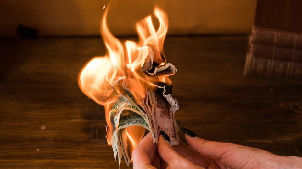 Eine Frau hält brennende Geldscheine in ihren Händen