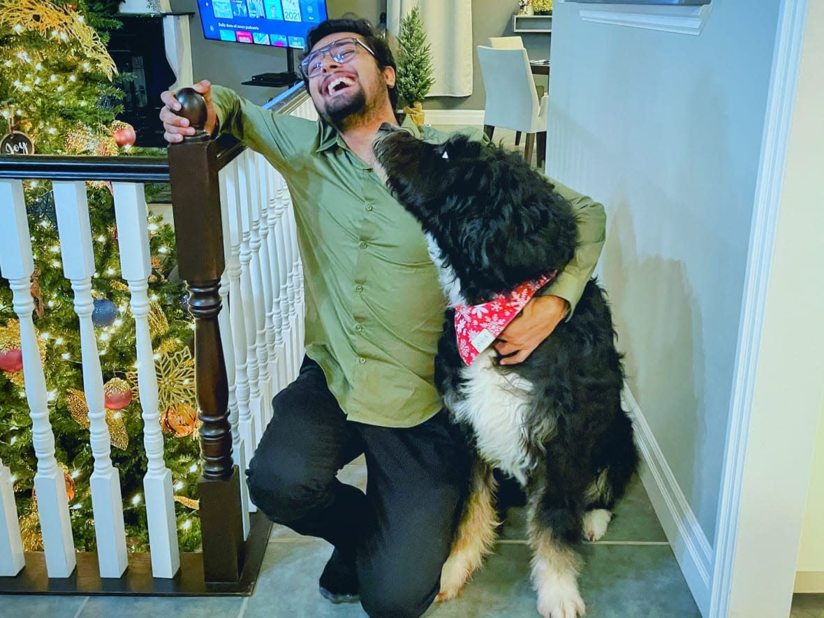 Harsh Patel attended one of his first Christmas dinner parties at instructor Darryl Veld's home last year as part of Brock University's Home for the Holidays, enjoying the food, festivities and Veld's dog Myles. (Submitted by Darryl Veld - image credit)