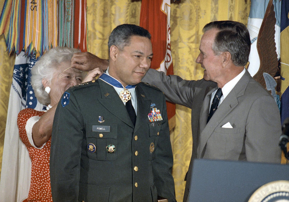 FILE - President George Bush loans his glasses to first lady Barbara Bush as she pins a Medal of Freedom on Gen. Colin Powell, chairman of the Joint Chiefs of Staff, during a White House ceremony, July 3, 1991. Powell, former Joint Chiefs chairman and secretary of state, has died from COVID-19 complications. In an announcement on social media Monday, Oct. 18, 2021 the family said Powell had been fully vaccinated. He was 84. (AP Photo/Doug Mills)