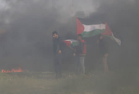 Palestinian demonstrators hold Palestinian flags during clashes with Israeli troops at a protest against Trump's decision on Jerusalem, near the border with Israel in the southern Gaza Strip March 9, 2018. REUTERS/Ibraheem Abu Mustafa