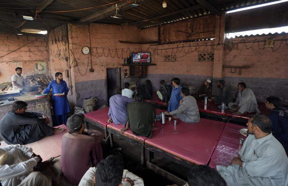 People watch a TV news report about the death of former Pakistani President Gen. Pervez Musharraf at a coffee shop in Karachi, Pakistan, Sunday, Feb. 5, 2023. Musharraf, who seized power in a bloodless coup and later led a reluctant Pakistan into aiding the U.S. war in Afghanistan against the Taliban, has died, officials said Sunday. He was 79. (AP Photo/Fareed Khan)