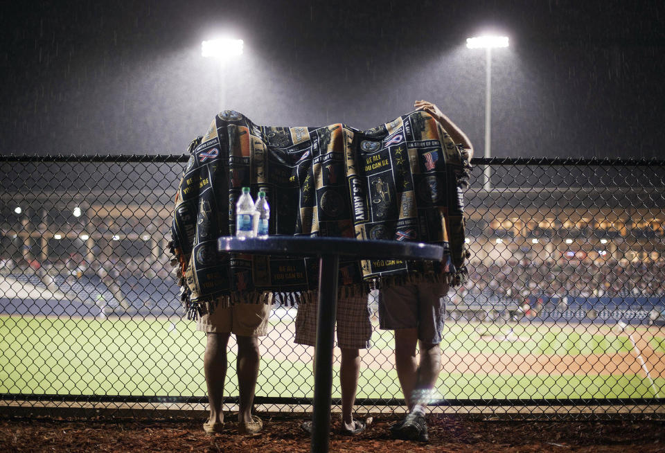 <p>Fans take shelter under a blanket during a rain delay in the seventh inning of an exhibition baseball game between the Atlanta Braves and the Atlanta Braves Future Stars on April 3, 2012, in Lawrenceville, Ga. (AP Photo/David Goldman) </p>