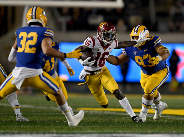 BERKELEY, CALIFORNIA - DECEMBER 04: Tahj Washington #16 of the USC Trojans stiff arms Luc Bequette.