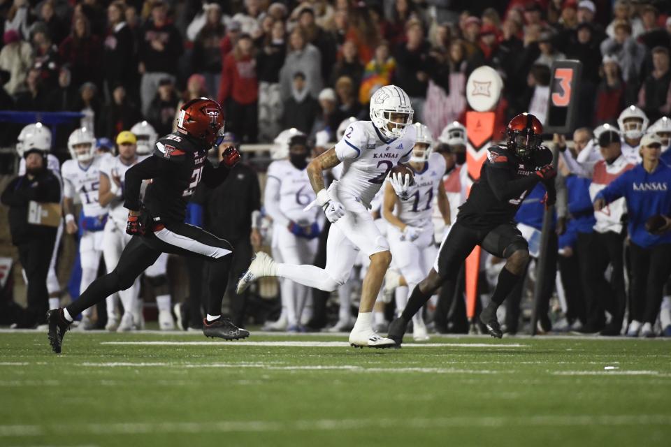 Kansas wide receiver Lawrence Arnold (2) runs with the ball against Texas Tech defensive back Dadrion Taylor-Demerson (25) and defensive back Marquis Waters during the first half of an NCAA college football game, Saturday, Nov. 12, 2022, in Lubbock, Texas. (AP Photo/Justin Rex)