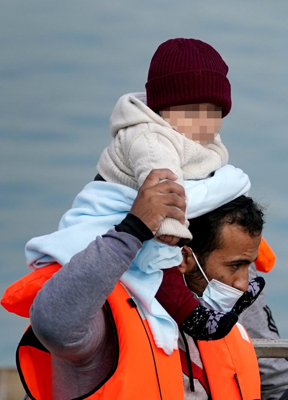 A man carrying a baby wrapped in blanket was among a group who were brought ashore in Kent on Friday (Gareth Fuller/PA) (PA Wire)