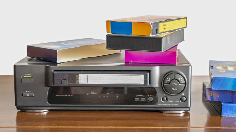 old videocassette player with old videotapes on a wooden cabinet