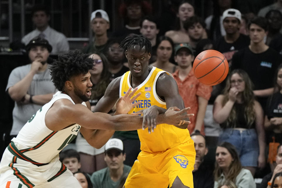Miami forward Norchad Omier (15) passes the ball past Pittsburgh center Federiko Federiko during the first half of an NCAA college basketball game, Saturday, March 4, 2023, in Coral Gables, Fla. (AP Photo/Rebecca Blackwell)