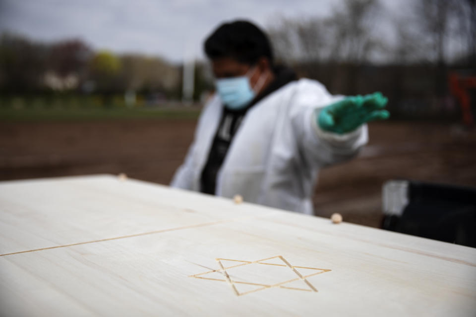 Gravedigger Thomas Cortez directs his coworker where to stop the pickup truck carrying a casket as it's brought to a plot for burial at Hebrew Free Burial Association's Mount Richmond Cemetery in the Staten Island borough of New York, Wednesday April 8, 2020. Two of Cortez' friends have fallen ill and he and his colleagues worry they will too. It is sad work, he admits, but it must continue. Another funeral is about to begin. (AP Photo/David Goldman)