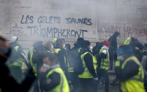 The slogan "The yellow vests will triumph" is seen on the Arc de Triomphe as protesters demonstrate at the Place de l'Etoile in Paris - Credit: Reuters