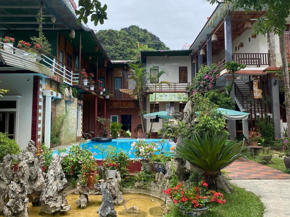 External view of a hostel with a pool and plants.