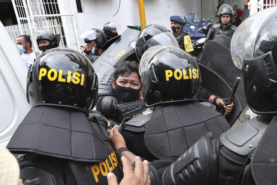 Police officers detain a supporter of Rizieq Shihab, leader of the Islam Defenders Front, during a rally in Jakarta, Indonesia, Friday, Dec. 18, 2020. Hundreds of protesters marched in Indonesia's capital on Friday to demand the release of the firebrand cleric who is in police custody on accusation of inciting people to breach pandemic restrictions and ignoring measures to curb the spread of COVID-19 by holding several events, and justice for his six followers who were killed in a shootout with the police. (AP Photo/Tatan Syuflana)