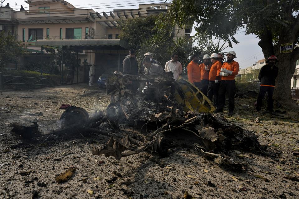 Security officials examine the wreckage of a car at the site of bomb explosion, in Islamabad, Pakistan, Friday, Dec. 23, 2022. A powerful car bomb detonated near a residential area in the capital Islamabad on Friday, killing some people, police said, raising fears that militants have a presence in one of the country's safest cities. (AP Photo/Anjum Naveed)