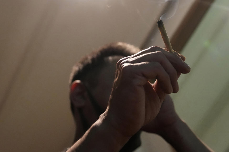 A Japanese tourist smokes cannabis at a Dutch passion shop in Bangkok, Thailand, Tuesday, June 27, 2023. Thailand’s de facto legalization of marijuana last year has brought a wave of tourists from the region intrigued by the lure of the forbidden leaf. (AP Photo/Sakchai Lalit)