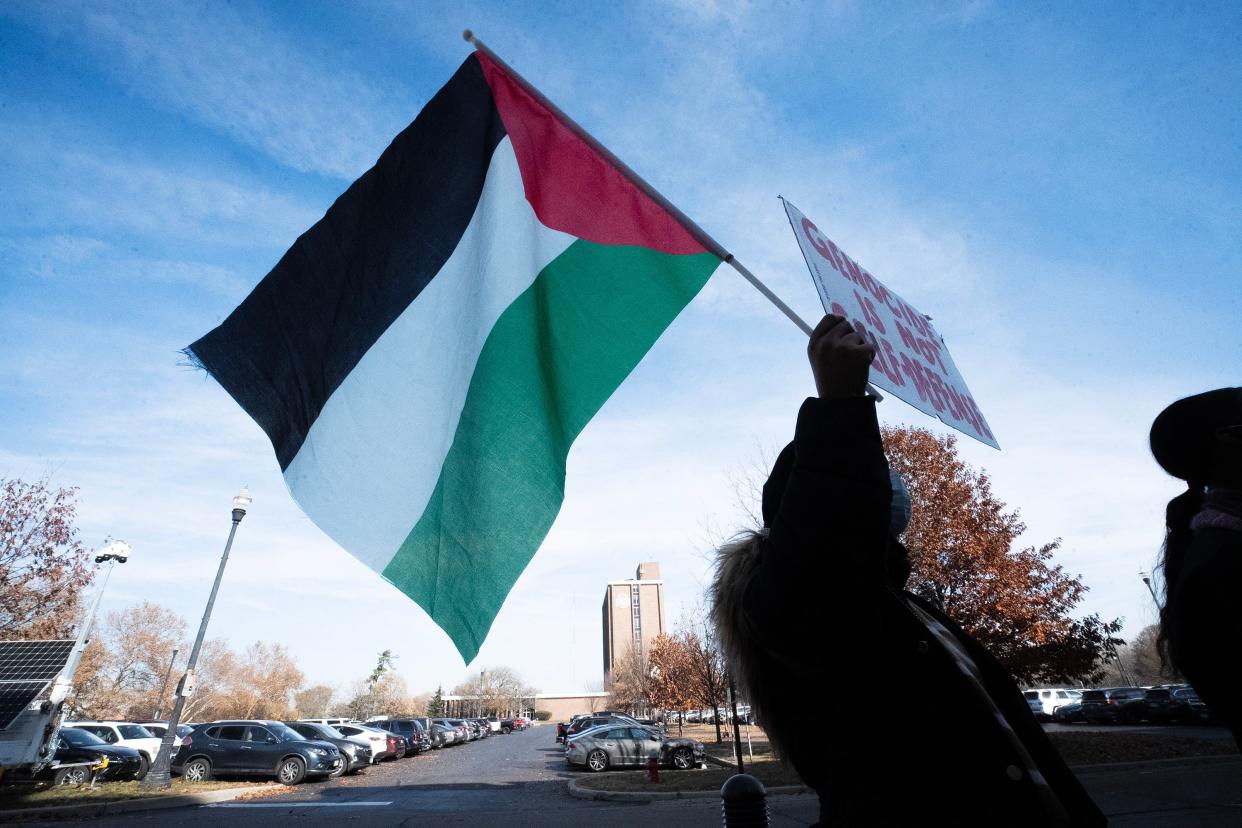 Nov 16, 2023; Columbus, Ohio, USA; A protestor holds a Palestinian flag on the front steps of The Ohio State University Longaberger Alumni House after they are made to leave the meeting. A demonstration was planned for protestors to speak during a meeting of the OSU Trustees calling for them to divest OSU funding from companies who have ties with Israeli fossil fuel companies operating in Palestine.