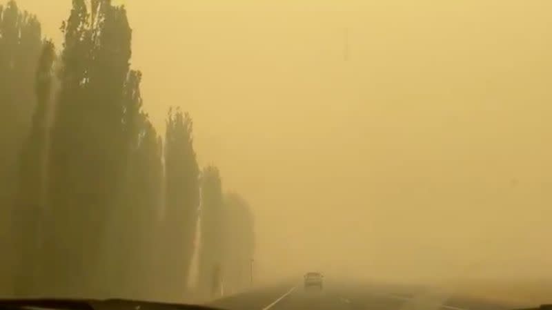 A vehicle is engulfed in yellowish smoke during bushfires near Cooma