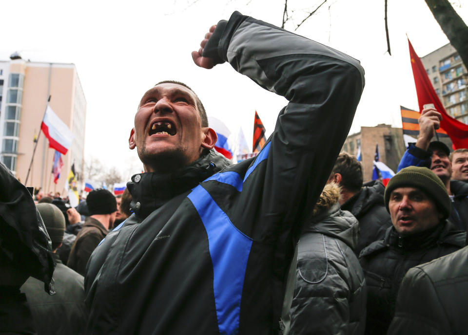 A pro-Russia demonstrator gestures as others storm the prosecutor-general's office during a rally in Donetsk, Ukraine, Sunday, March 16, 2014. Pro-Russia demonstrators in the eastern city of Donetsk called Sunday for a referendum similar to the one in Crimea as some of them stormed the prosecutor-general's office. (AP Photo/Andrey Basevich)