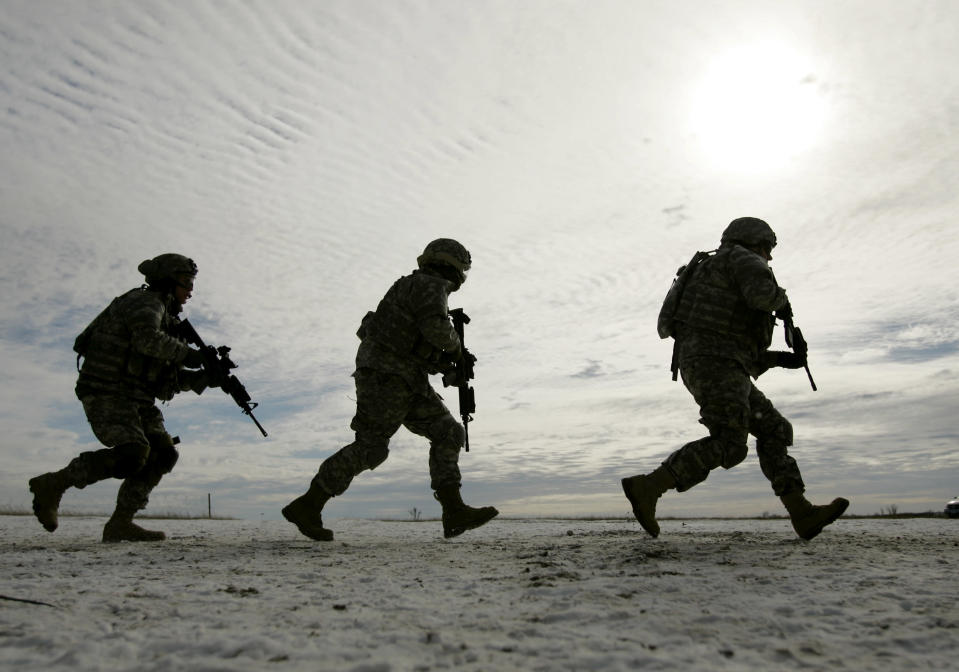 Soldiers from the 1st Infantry Division run across a frozen prairie as they train at Fort Riley, Kansas, Wednesday, Jan. 17, 2007. The soldiers from the division's fourth brigade will deploy to Iraq in the next few weeks as part of President Bush's planned troop surge. (AP Photo/Charlie Riedel)