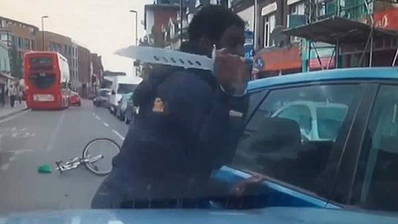 Ciclista mostrando el enorme cuchillo que traía para atacar al automovilista. Foto: Youtube.com/ Daily Mail
