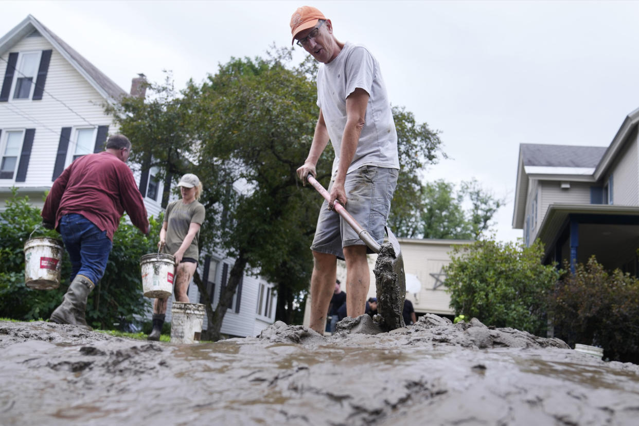 A man shovels mud away from his home.