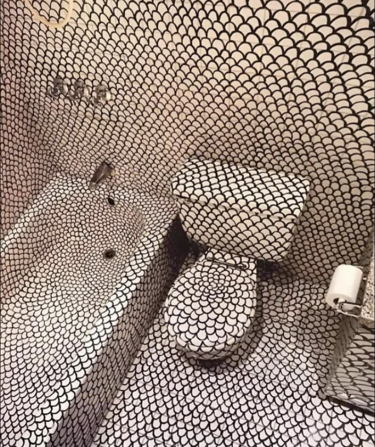 A bathroom with toilet, bidet, and sink covered in matching patterned tiles