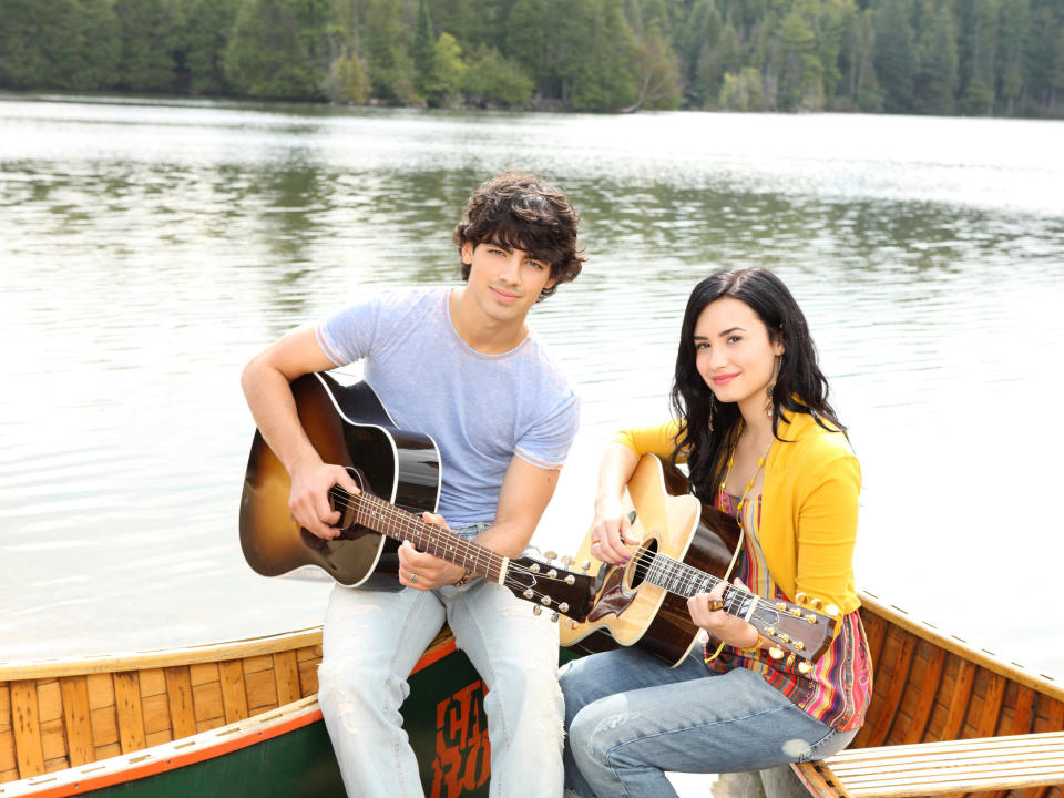 demi and joe playing guitars on a canoe