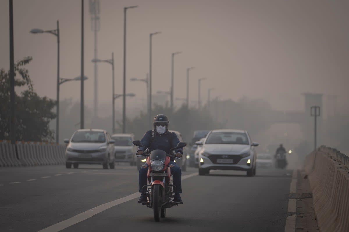 A motorcyclist drives wearing pollution mask amid smog in Delhi (AP)