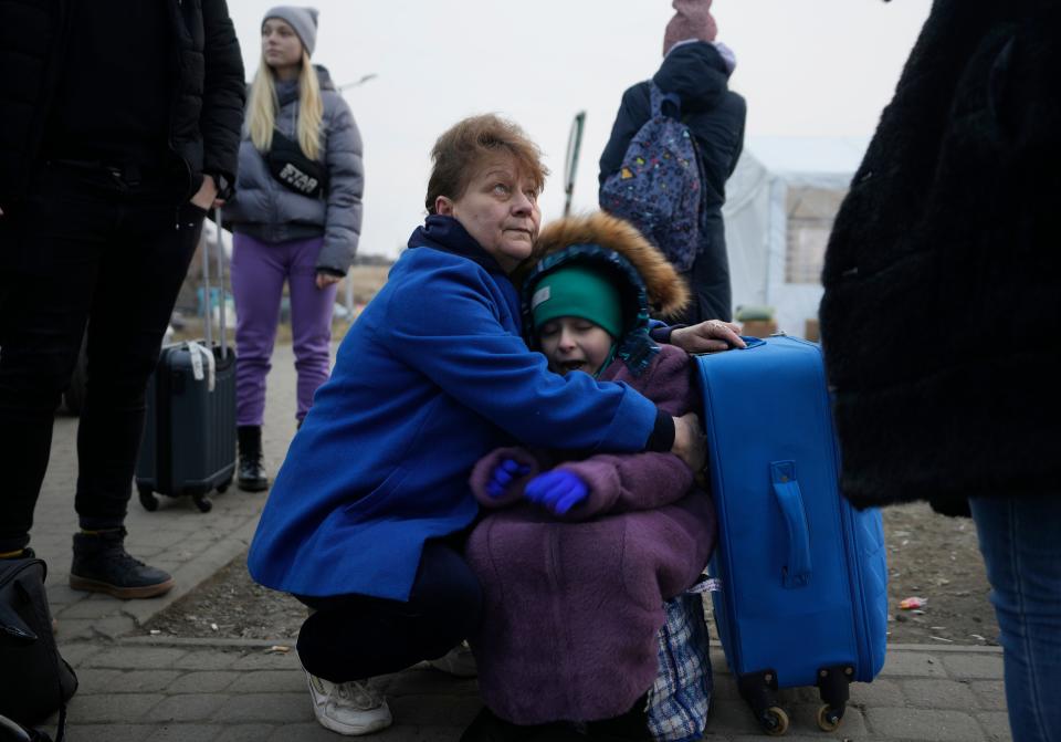 A woman holds a small girl at a border crossing, up as refugees flee a Russian invasion, in Medyka, Poland.