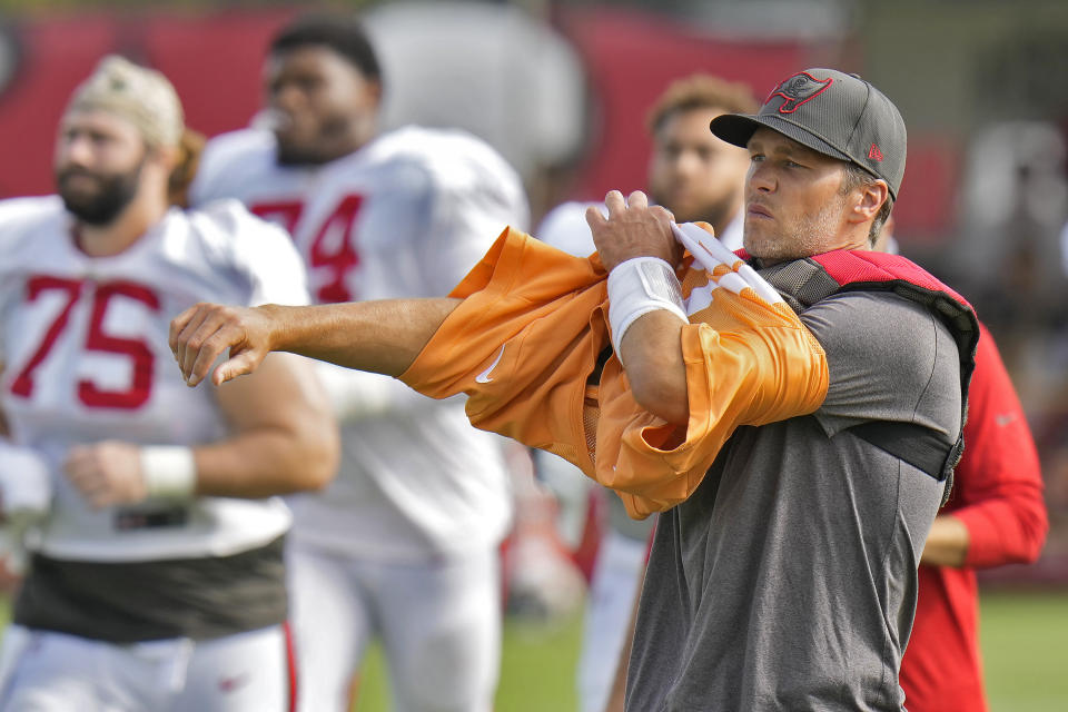 Tampa Bay Buccaneers quarterback Tom Brady puts on his jersey during an NFL football training camp practice with the Miami Dolphins Wednesday, Aug. 10, 2022, in Tampa, Fla. (AP Photo/Chris O'Meara)