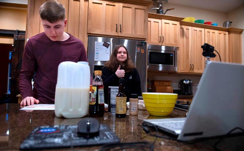 Camrynn Anderson, 11, gives a thumbs up to indicate she and her brother, Ryan Anderson, 13, are ready to begin preparing a meatloaf during the weekly after-school ZOOM cooking class from their home in Gig Harbor, Washington.