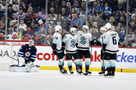 Seattle Kraken's Tye Kartye (52) celebrates his goal on Winnipeg Jets goaltender Connor Hellebuyck (37) with teammates during the second period of an NHL hockey game in Winnipeg, Manitoba on Tuesday April 16, 2024. (Fred Greenslade/The Canadian Press via AP)