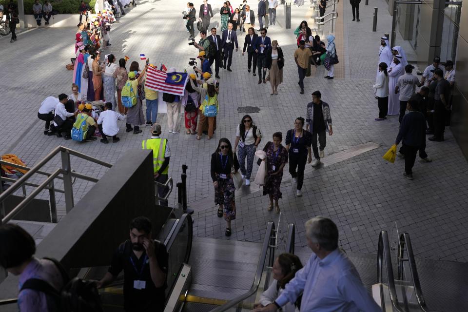 FILE - People walk past demonstrators as they arrive at the COP28 U.N. Climate Summit, Thursday, Nov. 30, 2023, in Dubai, United Arab Emirates. (AP Photo/Rafiq Maqbool, File)