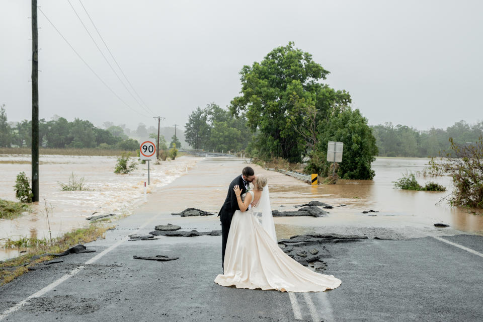 Bride and groom kiss in front of flood waters