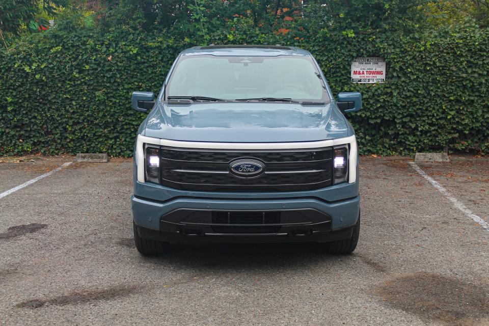 The 2023 Ford F-150 Lightning Platinum, viewed from the front, in a parking lot.
