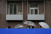 FILE - Residents holding umbrellas line up in the rain along the barricaded fence for COVID tests outside the locked-down apartment building on Wednesday, April 27, 2022, in Beijing. (AP Photo/Andy Wong, File)