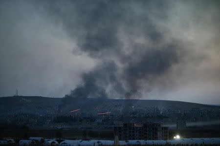 Smoke rises from the Syrian town of Kobani, seen from near the Mursitpinar border crossing on the Turkish-Syrian border in the southeastern town of Suruc in Sanliurfa province on October 26, 2014. REUTERS/Kai Pfaffenbach