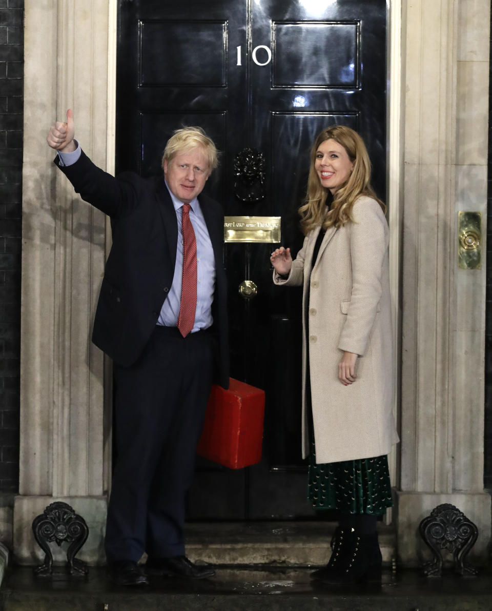 Britain's Prime Minister Boris Johnson and his partner Carrie Symonds wave from the steps of number 10 Downing Street in London, Friday, Dec. 13, 2019. Prime Minister Boris Johnson's Conservative Party has won a solid majority of seats in Britain's Parliament — a decisive outcome to a Brexit-dominated election that should allow Johnson to fulfill his plan to take the U.K. out of the European Union next month. (AP Photo/Matt Dunham)