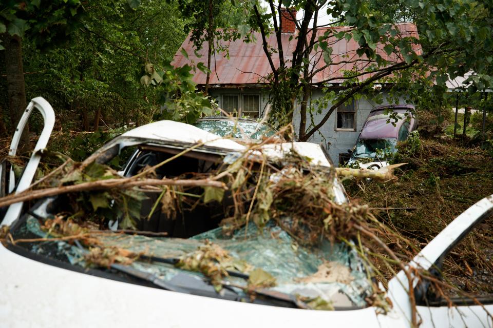 Destroyed cars are covered in debris from flooding and rain (AP)