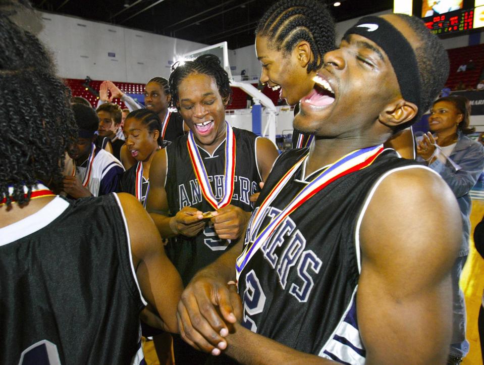 Dwyer Panthers' Leemire Goldwire, right,  celebrates his championship medal with teammates Corey Young, left center, and Alonzo Gee, second Right, after defeating Lake Howell Silver Hawks during the Boys Class 5A FHSAA State Championship game at the Lakeland Center  in Lakeland. Friday March 12, 2004.