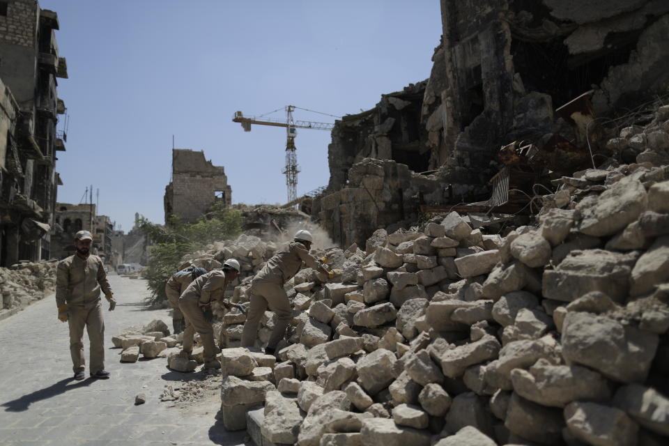 In this Saturday, July 27, 2019 photo, Syrian workers remove rubble from damaged shops in the old city of Aleppo, Syria. Much of Aleppo's centuries-old covered market is still in ruins but slowly small parts of it have been renovated where business is slowly coming back to normal nearly three years after major battles in Syria's largest city and once commercial center came to an end. (AP Photo/Hassan Ammar)