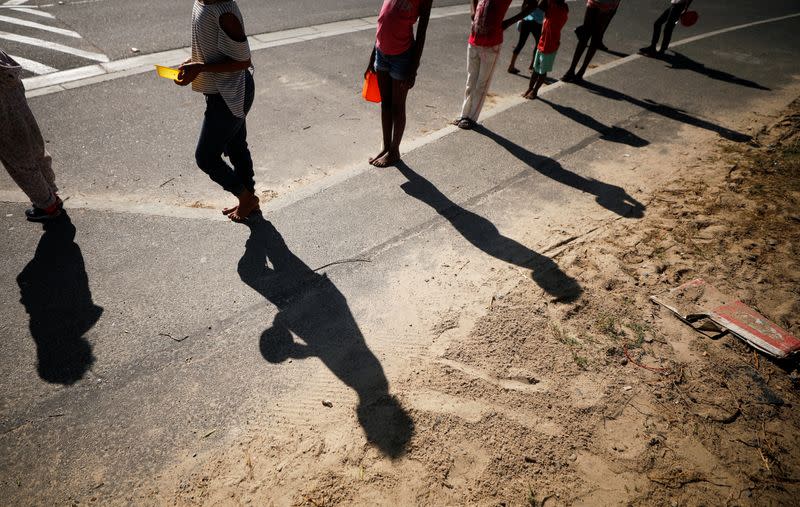 Children queue for food at a school feeding scheme during a nationwide lockdown aimed at limiting the spread of the coronavirus disease (COVID-19) in Blue Downs township near Cape Town