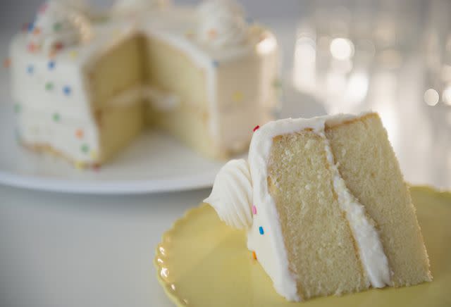 <p>Jamie Grill/Getty Images</p> Stock image of a slice of cake with the cake in the background