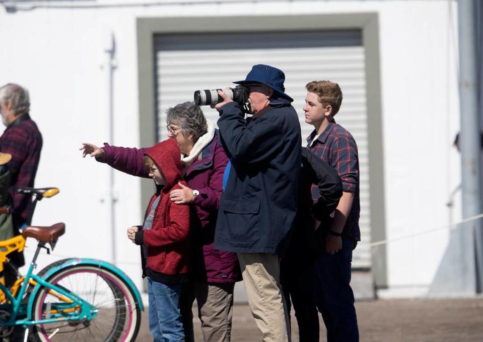 People watch and take photos of a gray whale swimming in the Morro Bay Harbor near Morro Rock on Thursday, March 14, 2024. The whale has been been spotted in the harbor for the last few days.