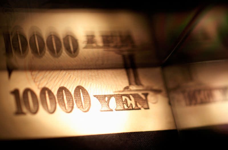 FILE PHOTO: Light is cast on a Japanese 10,000 yen note as it's reflected in a plastic board in Tokyo, in this picture illustration