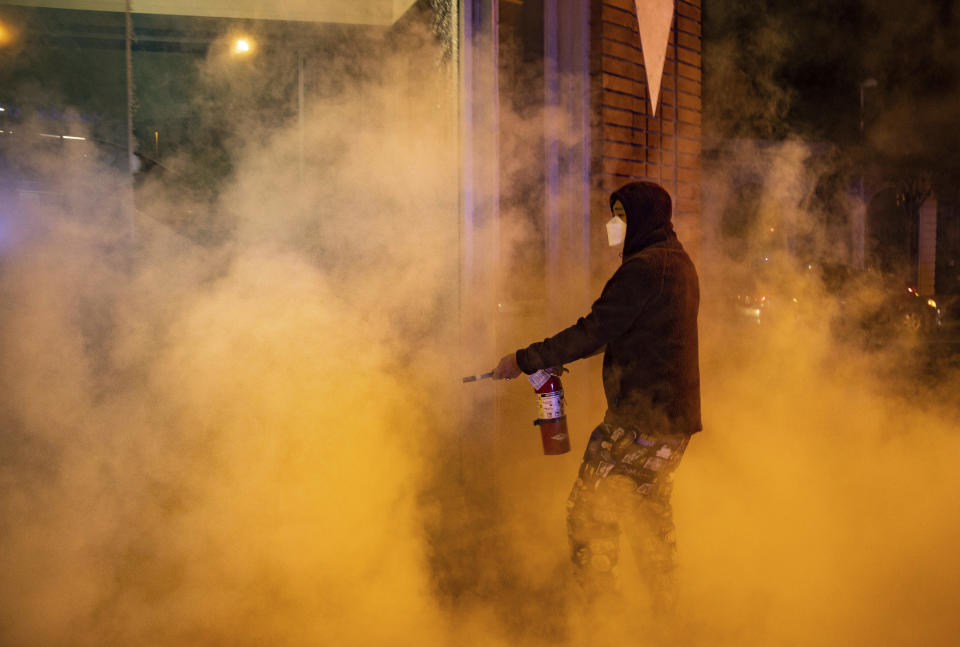 Demonstrators set fire to the front of the California Bank and Trust building during a protest against police brutality in Oakland, Calif., on Friday, April 16, 2021. (AP Photo/Ethan Swope)