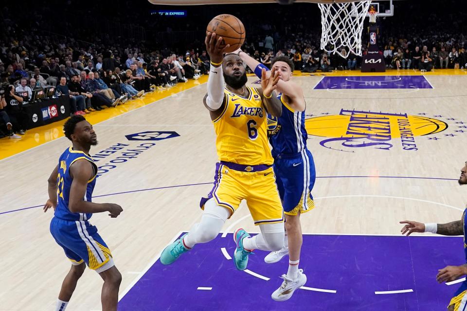 LeBron James drives to the basket as Klay Thompson defends.